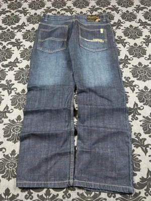 Blåa Southpole jeans med raka ben - Säljer ett par blåa jeans från Southpole med raka ben och kontrastsömmar. Jeansen har två bakfickor med dekorativa sömmar och en klassisk patch med logga bak i midjan. Perfekta för en avslappnad streetstil. De kan även ses som bootcut jeans. FÖR FLER FRÅGOR: DM