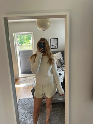 Vit fluffig stickad tröja - Mysig vit stickad tröja med fluffig textur och rund hals. Tröjan har långa ärmar och en rak passform, perfekt för att hålla värmen under kyliga dagar. Fint skick, strl S🤍