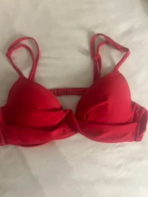 Röd bikiniöverdel från Nelly - Snygg röd bikiniöverdel med vaddering inuti, push-up. Justerbara band samt knäppning bak. Banden har blivit lite ”stela” men inget som syns. 