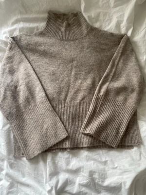 Beige stickad polotröja  - Beige stickad polotröja från Gina Tricot med slit i sidorna och ribbstickade kanter 