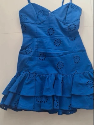  Ny slutsåld  kort klänning med volanger från Zara  - Supersöt blå kort klänning med smala axelband och volangkant nertill. Klänningen har broderade blommönster och en figurnära passform upptill. Perfekt för varma dagar och somriga vibes.