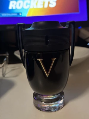 Paco Rabanne Invictus Victory EdP - Snygg parfymflaska från Paco Rabanne, modell Invictus Victory EdP. Flaskan är svart med guldigt V på framsidan och har en unik pokalformad design med genomskinlig botten. Perfekt för dig som gillar stilrena och moderna dofter. Lite mer än hälften 