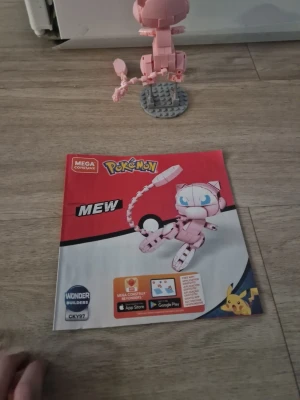 Mega Construx Pokémon Mew byggsats - Byggsats från Mega Construx föreställande Pokémon-figuren Mew. Modellen är ljusrosa och byggd av plastklossar, med rörlig svans och blå ögon. Instruktionsbok medföljer. Perfekt för Pokémon-fans som gillar att bygga egna figurer. Kommer med manual, den kommer inte uppbyggd.