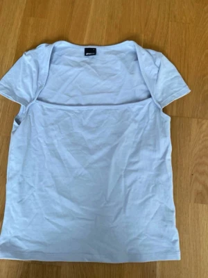 Vit kortärmad t-shirt från Gina Tricot - En basic vit t-shirt från Gina Tricot med korta ärmar och rund halsringning. Tillverkad i mjuk bomull, perfekt för en enkel och clean look. Passar till allt och är ett måste i garderoben.