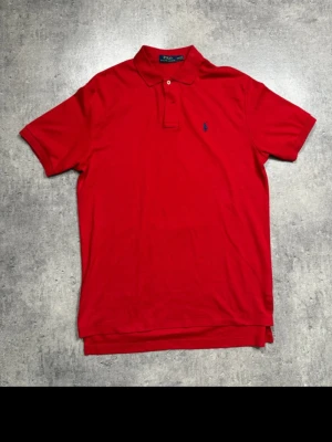 Ralph Lauren piké – röd M - Röd piké från Ralph Lauren i storlek M.  Snygg röd färg som alltid funkar.  Mycket bra skick. Säljs pga rensning.  Pris: 275 kr (kan diskuteras vid snabb affär)