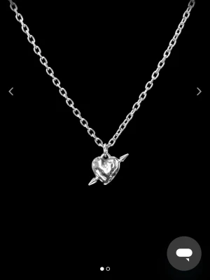 Maria Nilsdotter halsband  - Snyggt halsband i äkta silver med en kedja och ett unikt hjärthänge som har en pil genom sig. Perfekt accessoar för att ge din stil en edgy och romantisk touch. Passar till många olika outfits och är lätt att matcha. 