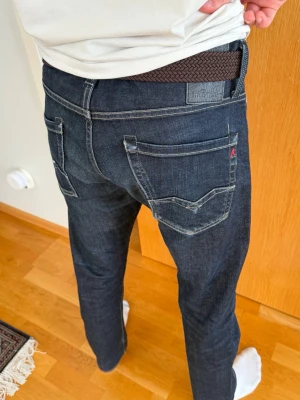 Mörkblå jeans från replay - Snygga mörkblå jeans från replay med raka ben och klassiska bakfickor med kontrastsömmar. Jeansen har en diskret logga på ena bakfickan och är tillverkade i denim med en stilren look. säljes pågrund av för stora i storlek för mig.