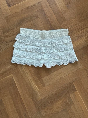Vita virkade shorts med volang - Snygga vita shorts med fina volanger. De har en feminin look med flera lager och vågig kant nertill. Perfekta för sommarens varma dagar. Är i storlek S/M