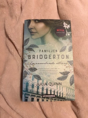 Familjen Bridgerton: En annorlunda allians - Säljer boken 'Familjen Bridgerton: En annorlunda allians' av Julia Quinn. Omslaget är grönt med blommönster och en bild på ett klassiskt hus. Perfekt för dig som gillar romantik och historiska romaner. Boken är på svenska och har en Netflix-serien baserad på den. 