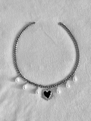 Silverhalsband med pärlor och hjärta - Kedjehalsband i silverfärg rostfritt stål med droppformade pärlor och ett svart hjärthänge med stråldetaljer. Snygg statement-accessoar som ger en cool och unik touch till din stil.