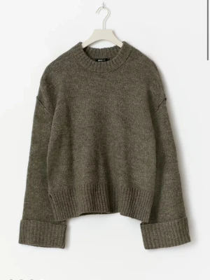 Brun stickad tröja med breda muddar - Mysig brun stickad tröja med rund halsringning och breda ribbade muddar vid ärmslut och nederkant. Nu utan prislapp, inga defekter, nypris 399,95kr