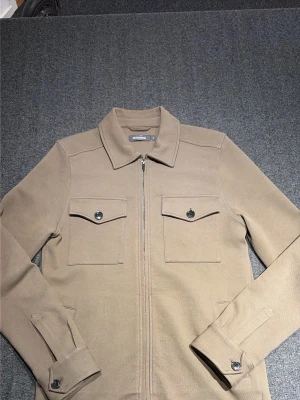 En olive grön overshirt från dressman - En snygg overshirt från dressman, inget fel på den, använd ett antal gånger men den är som helt ny kan man säga. PRISET är inte hugget i sten
