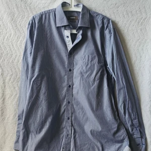 Blårandig skjorta från Ströms Stockholm  - Snygg blårandig skjorta från Ströms med klassisk krage och bröstficka. Skjortan har lång ärm, knappar framtill och en regular fit. Perfekt för en stilren look.