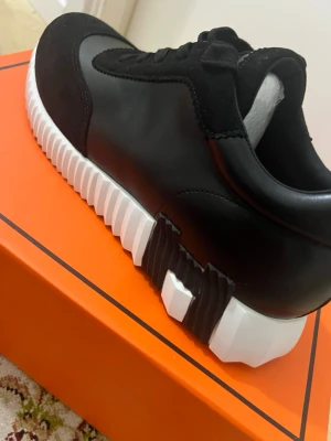 H- skor  - Stilrena svarta sneakers med coolt mönstrad vit sula. Ovandelen är i en mix av slätt läder och mocka, med svarta skosnören och detaljer. Snygg kontrast mellan material och färger, perfekt för dig som gillar en modern look.