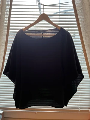 Svart loose topp med vida ärmar - En svart topp med lös passform och vida, nästan fladdriga ärmar. Toppen har rund halsringning och är tillverkad i ett mjukt, tunt material som faller snyggt. Perfekt för dig som gillar en avslappnad och stilren look. Original priset går på 370💕