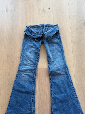 Blå bootcut jeans med detaljer - Blå flared jeans som är köpta second hand för 799kr men säljer för 379kr då dom är för små. Är i storlek 3. Passar som S. Har en skada som är vidad på sista bilden men i övrigt väldigt bra skick. 
