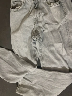 Ljusgrå raka jeans från h&m - Säljer ett par ljusgrå jeans från H&M med rak passform och klassisk femficksdesign. Jeansen är tillverkade i denim och har en avslappnad look som passar perfekt till en trendig streetstyle.
