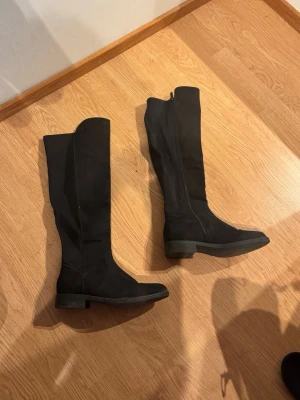 Svarta knähöga stövlar med dragkedja - Säljer ett par svarta knähöga stövlar med låg klack och dragkedja. I super bra skick💕