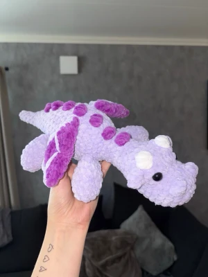 Virkad lila drake 🐉  - Virkad lila drake – handgjord & unik 🐉💜 En charmig och mjuk virkad drake i lila toner, perfekt som present, inredningsdetalj eller gosedjur för större barn • Draken är stadig men samtidigt mjuk och kramvänlig, och passar lika bra i barnrummet som på hyllan eller sängen 🐉 OBS! ⚠️ Innehåller säkerhetsögon – rekommenderas ej till barn under 3 år.