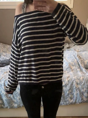Randig off-shoulder stickad tröja - Mysig stickad tröja med marinblå och vita horisontella ränder. Tröjan har en avslappnad passform och off-shoulder design som ger en trendig look. Fråga om du vill ha mera bilder. Passar M och S