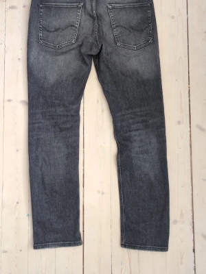 jack & jones jeans (32,34) - Säljer ett par grå tvättade jeans med raka ben och klassiska bakfickor. Jeansen har en snygg sliten look och är tillverkade i denim. Perfekta för en avslappnad och trendig stil. 