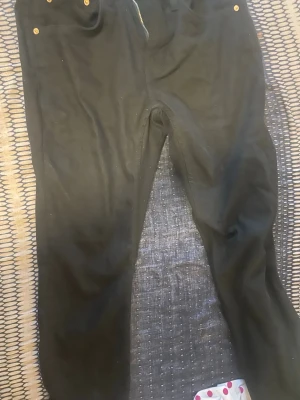 Svarta jeans från 157, storlek M - Säljer ett par svarta jeans från 157 i storlek M. Klassisk femficksmodell med dragkedja och gylf, samt guldfärgade nitar. Jeansen har rak passform och är tillverkade i ett mjukt bomullsmaterial. Perfekta för en clean och enkel look.