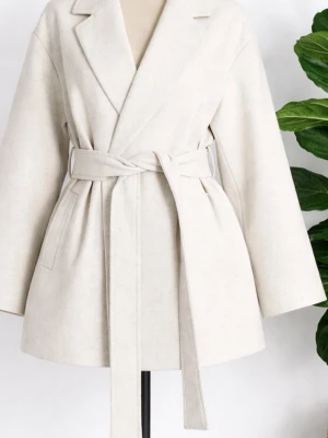 Beige kappa med knytskärp från 157 - Stilren beige kappa från 157 med breda slag, knytskärp i midjan och två fickor framtill. Kappan har en rak, något oversized passform och är fodrad. Perfekt för dig som gillar minimalistisk och trendig stil.