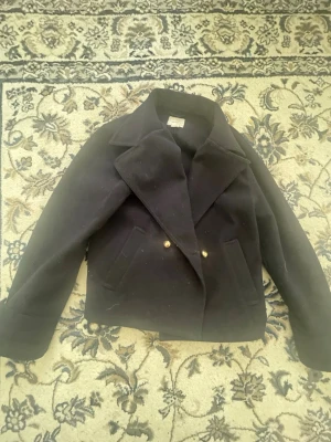 Mörk blå kappa  - Säljer en fin mörk blå kappa från Gina Young. Jackan är mörkblå och har guldiga knappar på. Säljer eftersom den inte passar mig och har använt den några därav priset. Köpte den för ca 350 men säljer den för 100kr.🗽🤍🫶🏽