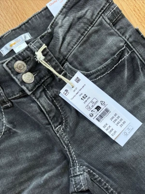 Svarta flared jeans från GinaTricot - Snygga low waist svarta jeans från GinaTricot med flared ben och slitna detaljer. Jeansen har dubbla silverknappar i midjan och klassiska fickor både fram och bak. Tillverkade i bomull med en cool tvättad look som passar perfekt till vardagsstilen. 