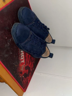 Christian Louboutin skor marinblå  - Snygga mörkblå sneakers i mocka med matchande blå skosnören och en unik röd sula. Klassisk låg modell med rund tå och diskret design. Perfekta för dig som gillar stilrena och bekväma skor med en twist. Kom med bud eller byten 