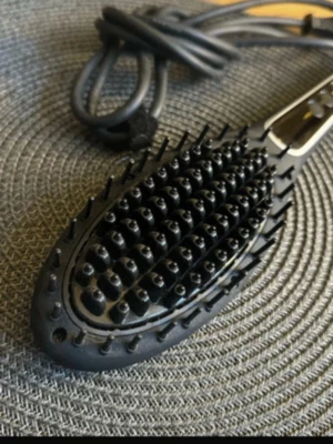 Svart elektrisk värmeborste - Elektrisk värmeborste i svart plast med digital display och knappar på handtaget. Borsten har täta piggar och lång sladd med stickkontakt. Perfekt för att styla och räta ut håret snabbt och smidigt.