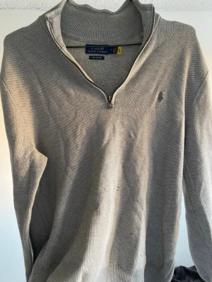 Grå halvzip-tröja från Polo Ralph Lauren - Snygg grå tröja från Polo Ralph Lauren i mjuk pima cotton. Perfekt för en stilren och avslappnad look. Stor flaw på bröstet som inte märks av jättemycket när man använder den, därav priset! ☺️ Priset är alltid förhandlingsbart!