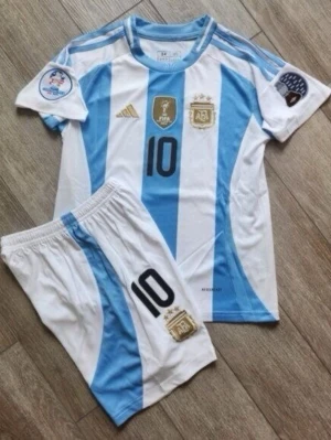 Argentina fotbollströja och shorts - Säljer ett set med Argentina fotbollströja och matchande shorts från Adidas. Setet är vitt och ljusblått med svarta detaljer, nummer 10 och flera officiella märken och loggor. Perfekt för fotbollsträning eller att heja på favoritlaget.