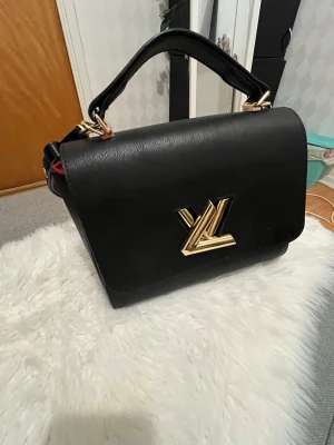 Svart Louis Vuitton handväska i läder - En svart Louis vitton-väska i fint sick. Väskan är använd men väl omhändertagen, med normala tecken på användning, har haft den ganska länge men har inte kommit till mycket användning drf väljer att sälja den nu. Dessutom har den bra material på tyget inuti. Pris kan diskuteras de bara att dma mig!💕 Bredd: 23 cm Höjd: 16 cm Djupt: 16 cm  Kvittot finns tyvärr inte kvar då jag har haft den i lång period och dessutom lådan till väskan. (det finns små fläckar, inte helt rent men de går att ta bort).