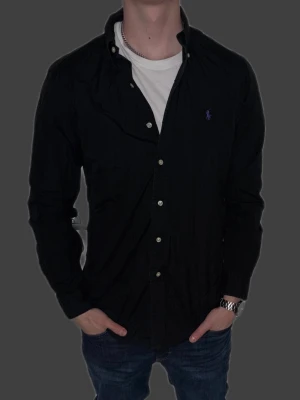 Svart skjorta från Ralph Lauren - Svart skjorta från Ralph Lauren i storlek M.  Fint skick till ett bra pris. Nypris: 1995kr. Mitt pris: 349kr. Vid frågor eller funderingar, tveka inte att höra av dig.