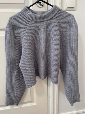 Grå ribbstickad tröja - En stilren grå ribbstickad tröja med lång ärm och lite croppad 