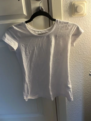 Vit t-shirt från Basic You - Klassisk vit t-shirt från Basic You i ekologisk bomull. Modellen har rund halsringning och korta ärmar, perfekt för en enkel och clean look. Passformen är figurnära och materialet känns mjukt mot huden.