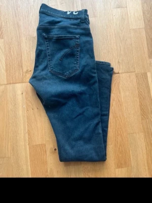 Mörkblå dondup slim jeans - Snygga mörkblå slim fit jeans med klassisk femficksdesign och dragkedjegylf. Jeansen har en smal passform och är tillverkade i stretchigt denimtyg som ger en bekväm känsla. Perfekta till en avslappnad look.