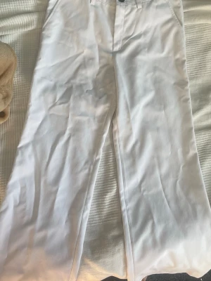 Vita raka kostymbyxor - Säljer ett par vita chinos med rak passform och klassisk design. Byxorna har fickor i sidorna och är tillverkade i ett mjukt bomullstyg som känns skönt mot huden. Perfekta för dig som vill ha en clean och stilren look. Det finns ingen lapp som visar varken märke eller storlek. De är för små för mig som är 170. Skulle nog säga att de passar 134-158. Faktiskt ingen aning, kan mäta om det behövs. Aldrig andvända fint skick. Säljer då jag rensar min garderob. Skriv om ni har frågor!