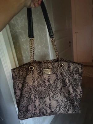 Victoria’s secret väska - Sjukt snygg väska från Victorias secret i beige med svart spets och guld. Köpt från Vinted nyligen och säljer då den inte rymde det jag behövde ha i 💓 superbra skick, inga defekter förutom nån skrapa på guldplaterade märket.
