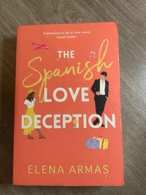 The Spanish Love Deception bok - En romantisk roman på engelska av Elena Armas med färgstarkt orange omslag och illustrationer av två personer, resväskor och ett flygplan. Perfekt för dig som gillar enemies-to-lovers och fake-dating-teman. Mjukpärm och modern design.
