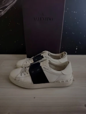 Valentino open  - Riktigt snygga marinblå/vita valentino open skor. Storleken är 43,5, då en av skorna är rätt slitna lägger jag de i ’’acceptabelt skick’’, det är bara en av skorna som är slitna vilket också syns på bilderna men ändå därav det extremt billiga priset. Skorna är självklart 100% äkta, (visas på sista bilden) endast skorna medföljer med köp. 
