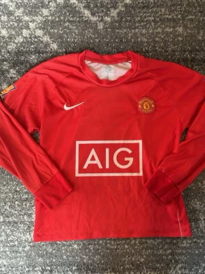 Manchester United långärmad tröja Dri-fit - Röd långärmad Manchester United-tröja från Dri- fir med klubbmärke på bröstet och AIG som sponsortryck. Tröjan har rund hals och är tillverkad i ett lätt och bekvämt material, perfekt för fotbollsträning eller match.CR7 på ryggen. Storlek S men liten i storlek passar typ xs/xss. Skick ses på bilderna.