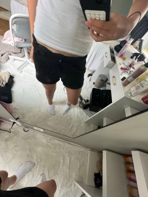 Svarta shorts med fickor - Snygga svarta shorts med normal passform och klassisk design. Shortsen har bälteshällor, två bakfickor och är tillverkade i ett mjukt bomullsmaterial. Perfekta för varma dagar och enkla att matcha med olika stilar.
