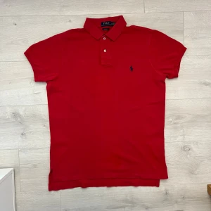 Ralph lauren pike röd - Säljer en klassisk röd piké från Ralph Lauren. Ett tidlöst plagg som passar perfekt till både vardag och lite mer uppklädda tillfällen.  • Storlek: M • Färg: Röd • Skick: Mycket fint skick • Klassisk passform med broderad Ralph Lauren-logga • Mjuk och bekväm kvalitet • Perfekt att matcha med jeans, shorts eller chinos