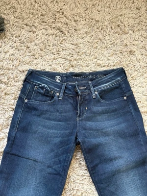 Mörkblå jeans med dragkedjor bak - Säljer ett par mörkblå jeans med snygg tvätt och slitningar. Jeansen har fem fickor fram och två bakfickor med dragkedjor samt ett bälte bak i midjan. Klassisk rak passform och coola detaljer som ger en modern look. Inte utsvängda🫶