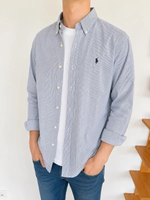 Randig skjorta från Polo Ralph Lauren - Snygg blåvit randig skjorta från Polo Ralph Lauren i slim fit-modell. Skjortan har klassisk krage, knappar framtill och broderad logga på bröstet. Perfekt till jeans eller chinos för en stilren look.