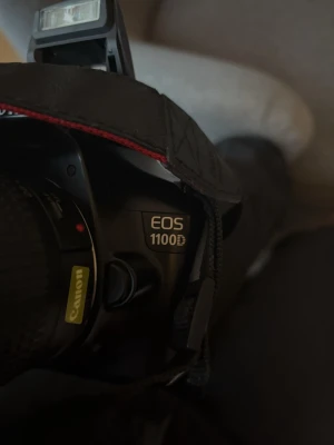 Canon EOS 1100D systemkamera svart - Canon EOS 1100D är en svart digital systemkamera med tydlig display, inbyggd blixt och klassisk Canon-rem. Kameran har ergonomiskt grepp och flera knappar för smidig kontroll. Perfekt för dig som vill ta snygga bilder med en riktig kamera. Ladare, Minneskort 64 mg  extra batteri och kvittot ingår även själva linsen. Kommer med 