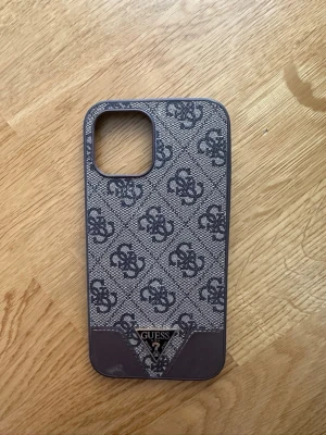 Mobilskal iPhone 12 Pro Max - Snyggt mobilskal från GUESS till iPhone 12 Pro Max.  Det finns en mindre kosmetisk skada/slitage längst ner på kanten (se bild), men den påverkar inte användningen.