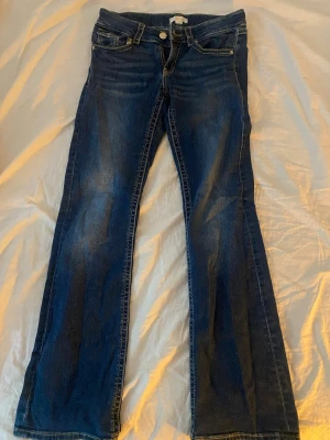 Blå bootcut jeans från Gina Tricot - Säljer ett par blå bootcut jeans från Gina Tricot i storlek 164. Jeansen har klassisk femficksmodell, normal midja och snygga slitningar framtill. Perfekta till en avslappnad look och passar till det mesta i garderoben.